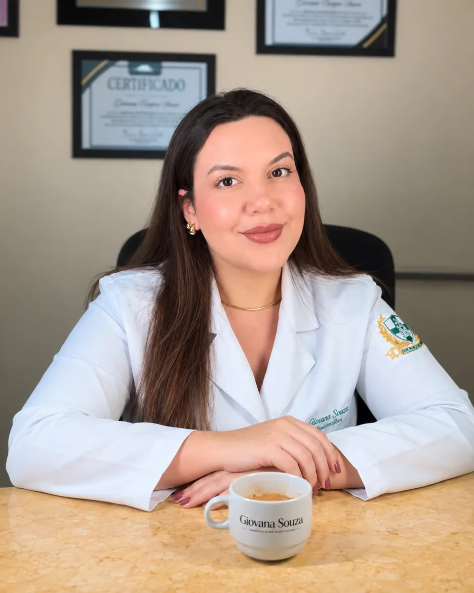 Giovana Souza de jaleco em sua sala de atendimento